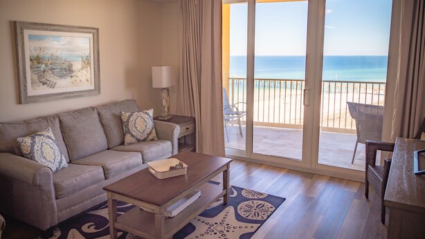 A living room with a sofa, coffee table, and a view of the beach through large sliding doors. - The Calypso Resort in PCB , Family Friendly,11 Floor, Free Beach Chairs Service (Panama City Beach)