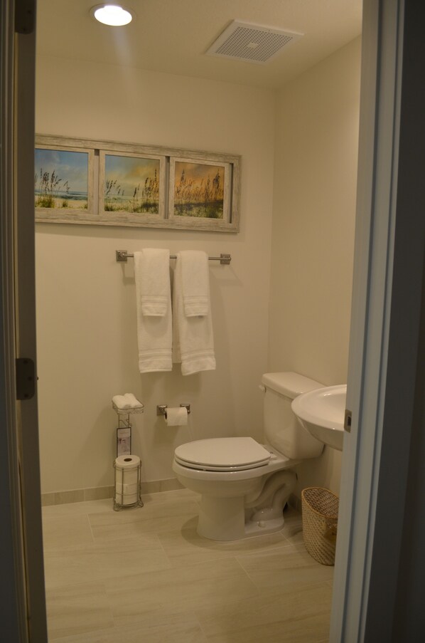 Une salle de bain avec des toilettes, un lavabo et deux serviettes suspendues à un porte-serviettes.