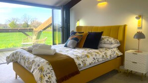 Ein Bett mit einer blumigen Tagesdecke, einem gelben Kopfteil und einer Nachttischlampe.