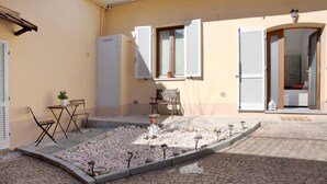 A courtyard with a paved area, a bench, a table, a potted plant, and a door with a window. - Holiday Apartment "Casa Vacanze La Porta in Piazza" with Terrace (guarene)