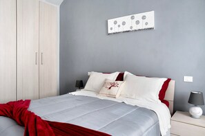 A bedroom with a bed, nightstands, a lamp, a wall art piece, and a wardrobe. - Holiday Apartment "Casa Vacanze La Porta in Piazza" with Terrace (guarene)