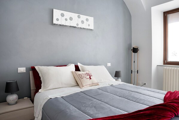 Ein Schlafzimmer mit Bett, Nachttischen, einer Stehlampe und Wandkunst.
