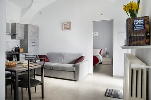 A modern kitchen with grey cabinets, a dining table with chairs, a grey sofa, and a radiator. - Holiday Apartment "Casa Vacanze La Porta in Piazza" with Terrace (guarene)