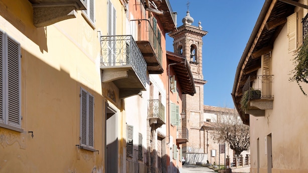 A narrow cobblestone street lined with historic buildings, a bell tower, and balconies with wrought iron railings. - Holiday Apartment "Casa Vacanze La Porta in Piazza" with Terrace (guarene)