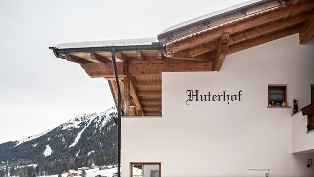 A building with a wooden exterior and a sign reading 'Hutterhof.'