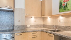 A kitchen with granite countertops, stainless steel appliances, wooden cabinets, and a wall-mounted sink.
