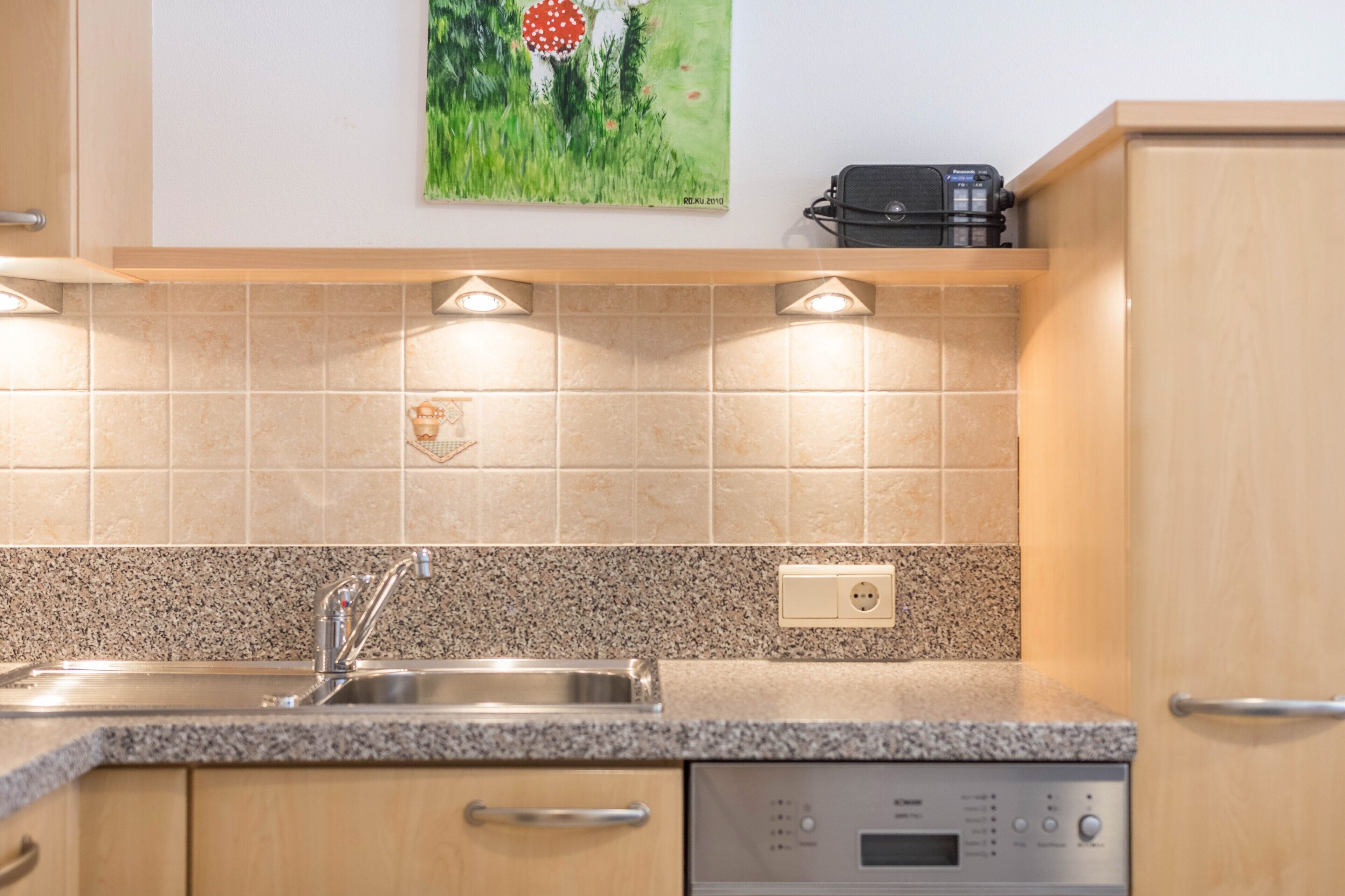 Een keuken met een granieten aanrecht, een roestvrijstalen spoelbak en een vaatwasser.