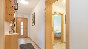 A hallway with a wooden door, a framed picture, and a bed in the adjacent room. - Apartment "Huterhof Talblick" with Mountain View, Balcony and Wi-Fi (Sarentino)