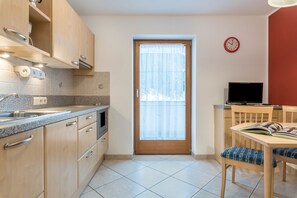 A kitchen with wooden cabinets, a built-in oven, a sink, and a window with a curtain.