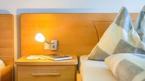 A neatly made bed with a pillow, a bedside lamp, a book, and a small drawer. - Apartment "Huterhof Talblick" with Mountain View, Balcony and Wi-Fi (Sarentino)