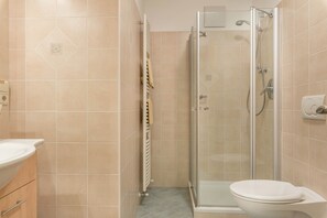 A bathroom with a toilet, a shower with a glass door, and a towel rack.
