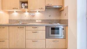 A kitchen with wooden cabinets, a built-in oven, and a granite countertop. - Apartment "Huterhof Talblick" with Mountain View, Balcony and Wi-Fi (Sarentino)