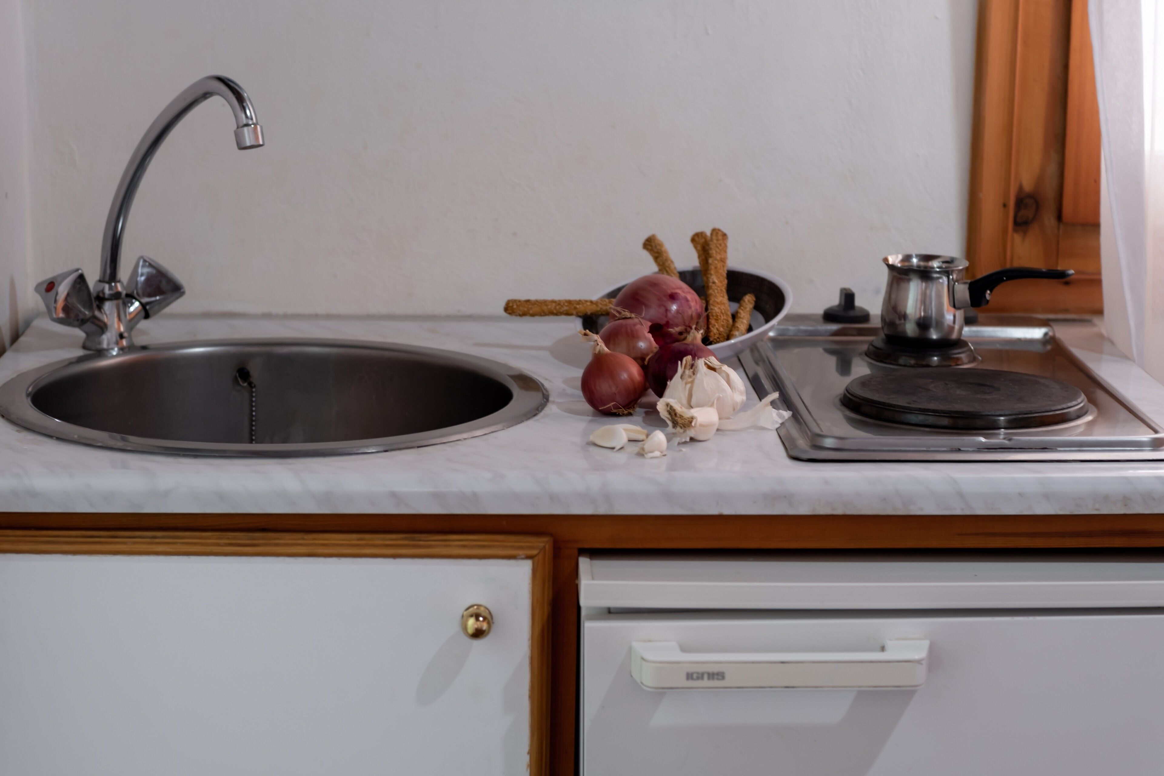 A kitchen with a sink, a stove, and a bowl of garlic cloves.