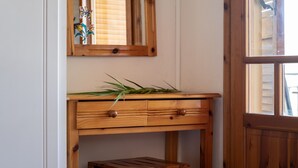 Un bureau en bois avec des tiroirs, un miroir et un petit tabouret en bois.