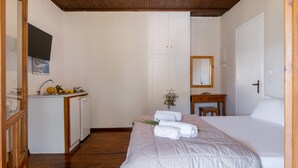 Ein Schlafzimmer mit Bett, Schreibtisch, Spiegel, Kleiderschrank und einer kleinen Küchenzeile.
