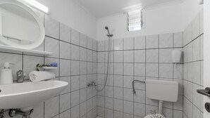 Ein Badezimmer mit Waschbecken, Spiegel, Dusche, Toilette und einem kleinen Fenster.