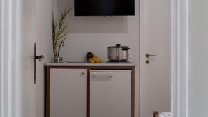 Eine Küchenzeile mit Flachbildfernseher, einem kleinen Schrank, einer Pflanze und Obst.