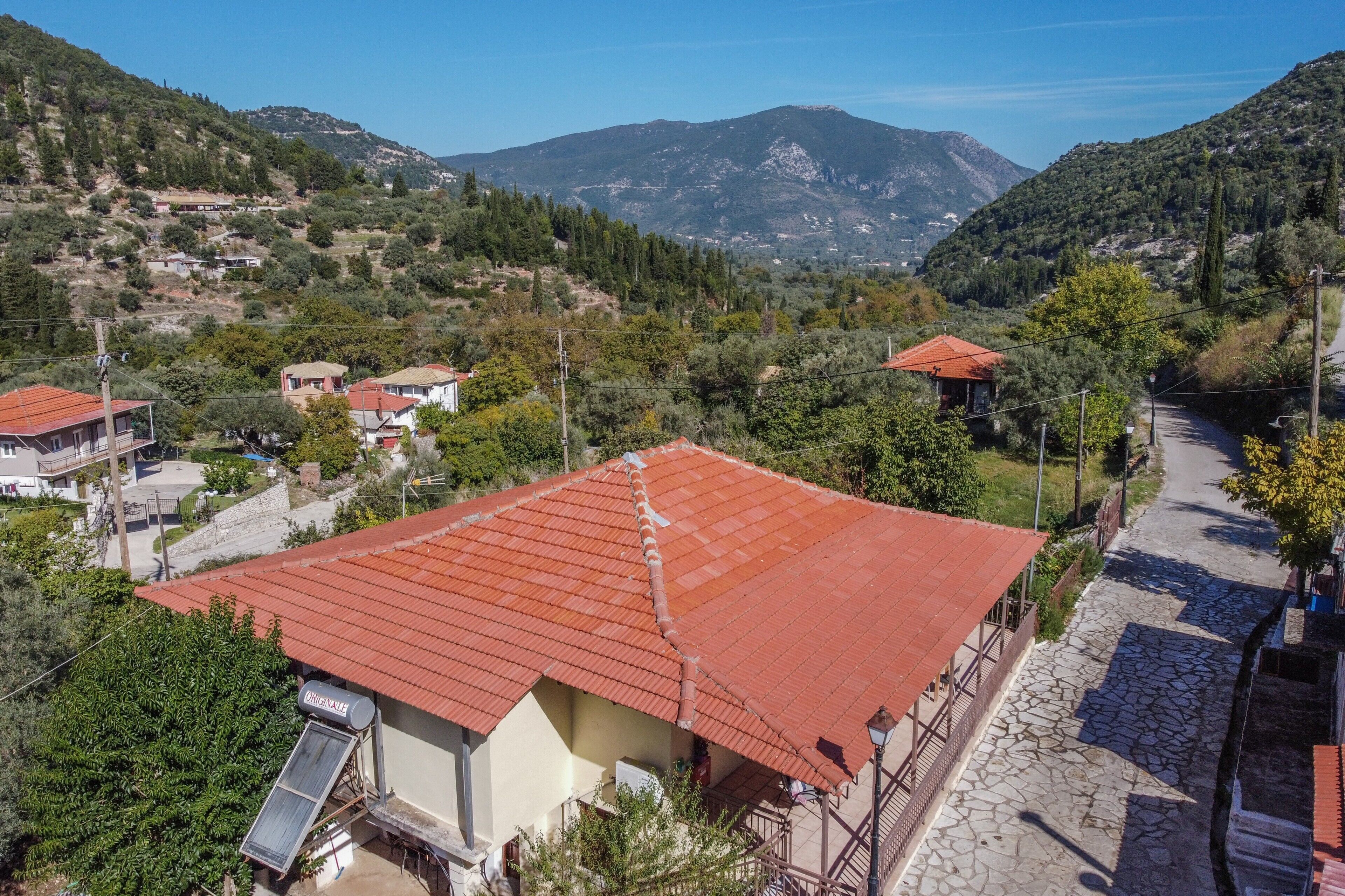 A rural village with traditional buildings, a stone pathway, and a mountainous backdrop.