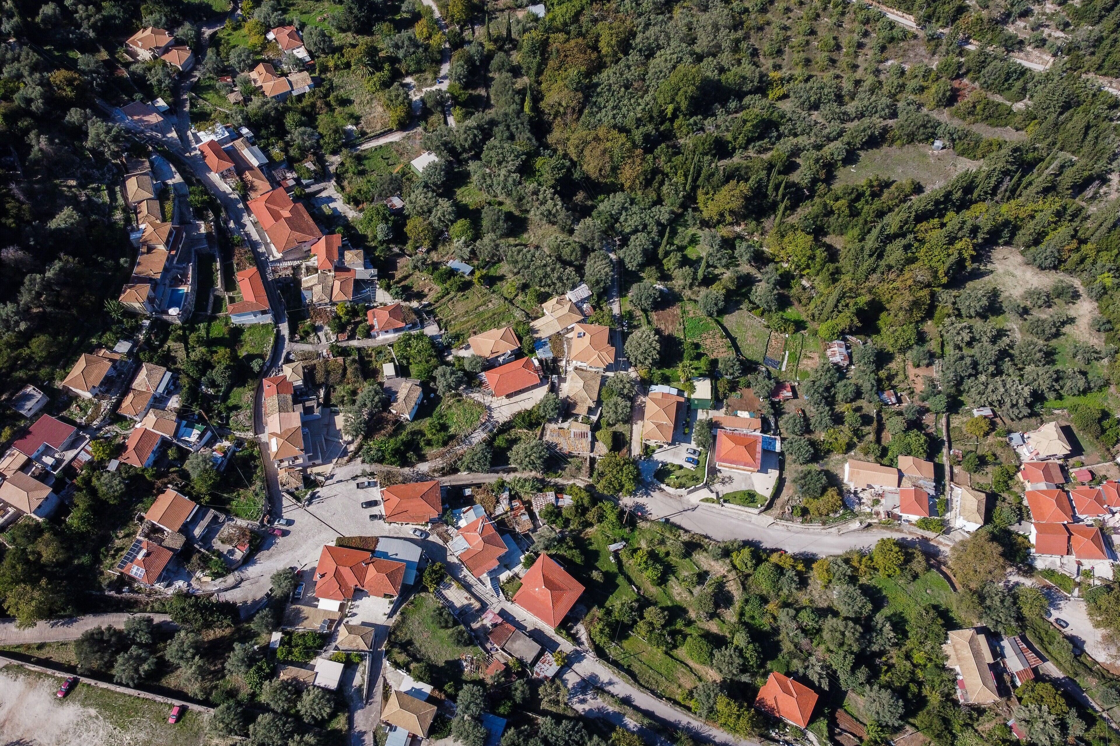 An aerial view of a residential area with houses, roads, and surrounding greenery.