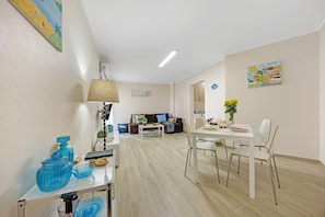 A modern living room with a sofa, coffee table, and dining area with chairs. - Apartment "Casa Azul" with Sea View, Balcony & Wi-Fi (Portimão)