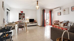 A modern living room with a dining area, a television, and a fireplace. - Apartment "Casa Farol" with Sea View, Balcony & Wi-Fi (Portimão)