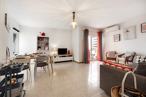 A modern living room with a dining area, a television, and a fireplace.