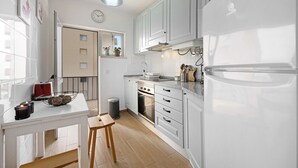 A modern kitchen with white cabinets, a built-in oven, and a refrigerator. - Apartment "Casa Farol" with Sea View, Balcony & Wi-Fi (Portimão)