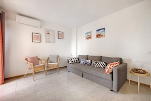 A living room with a grey sofa, wicker chairs, and a small table with a basket.