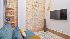 En moderne stue med sofa, et ur, et fjernsyn og en dekorativ vase.