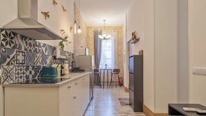 Et moderne køkken med et mønstret backsplash, en central ø og et spiseområde med et bord og stole.