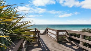 A wooden boardwalk leading to a beach with clear blue water and a palm tree on the left. - Beachfront Condo + Bikes, Community Pool & Views (Santa Rosa Beach)
