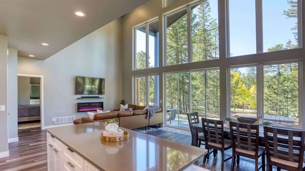 A spacious living area with a large island, a dining table with chairs, and a television mounted on the wall. - Sunset Ridge (Lead)