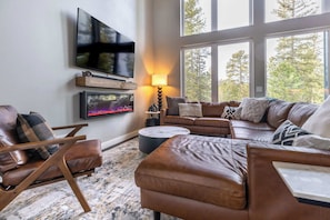 A living room with a large window, a flat-screen TV, a fireplace, and a leather sofa. - Sunset Ridge (Lead)