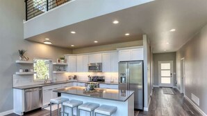 A spacious kitchen with a large island, stainless steel appliances, and a modern design. - Sunset Ridge (Lead)