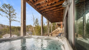 Ein Whirlpool unter einer Holzpergola mit Blick auf ein bewaldetes Gebiet.