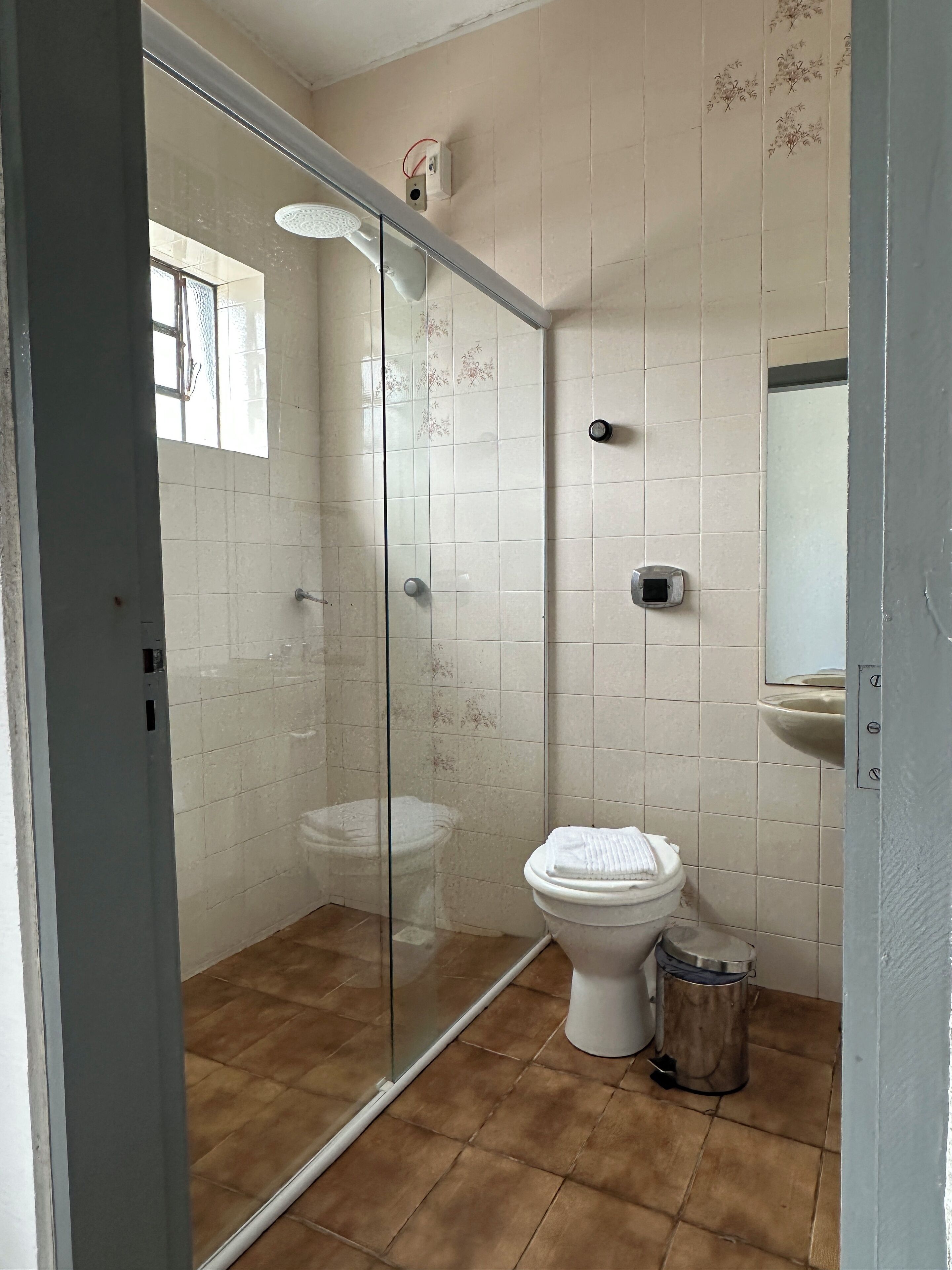 A bathroom with a glass-enclosed shower, a toilet, and a sink.