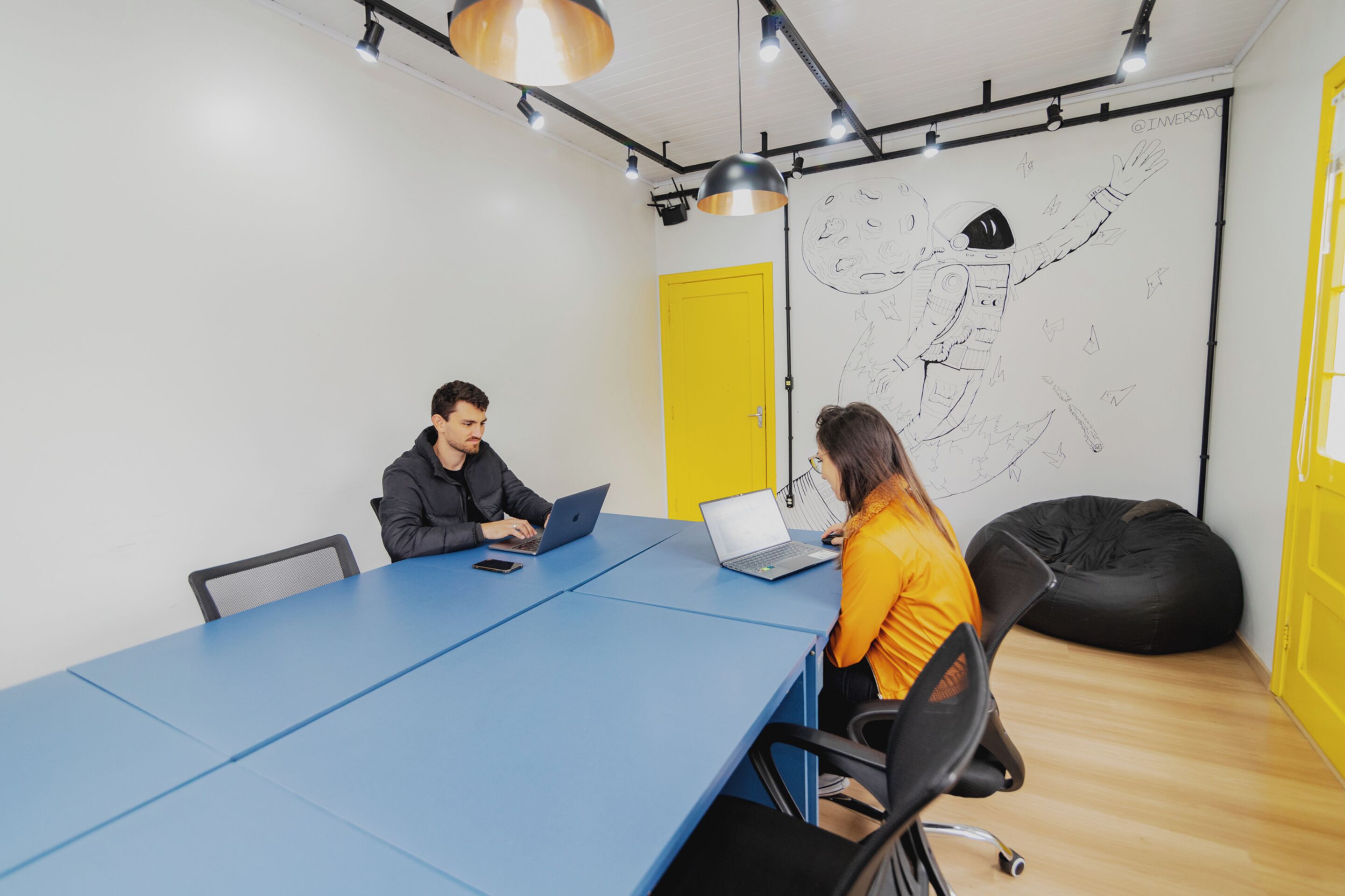 Una sala de reuniones con una mesa azul, dos portátiles y una pizarra grande con un dibujo.
