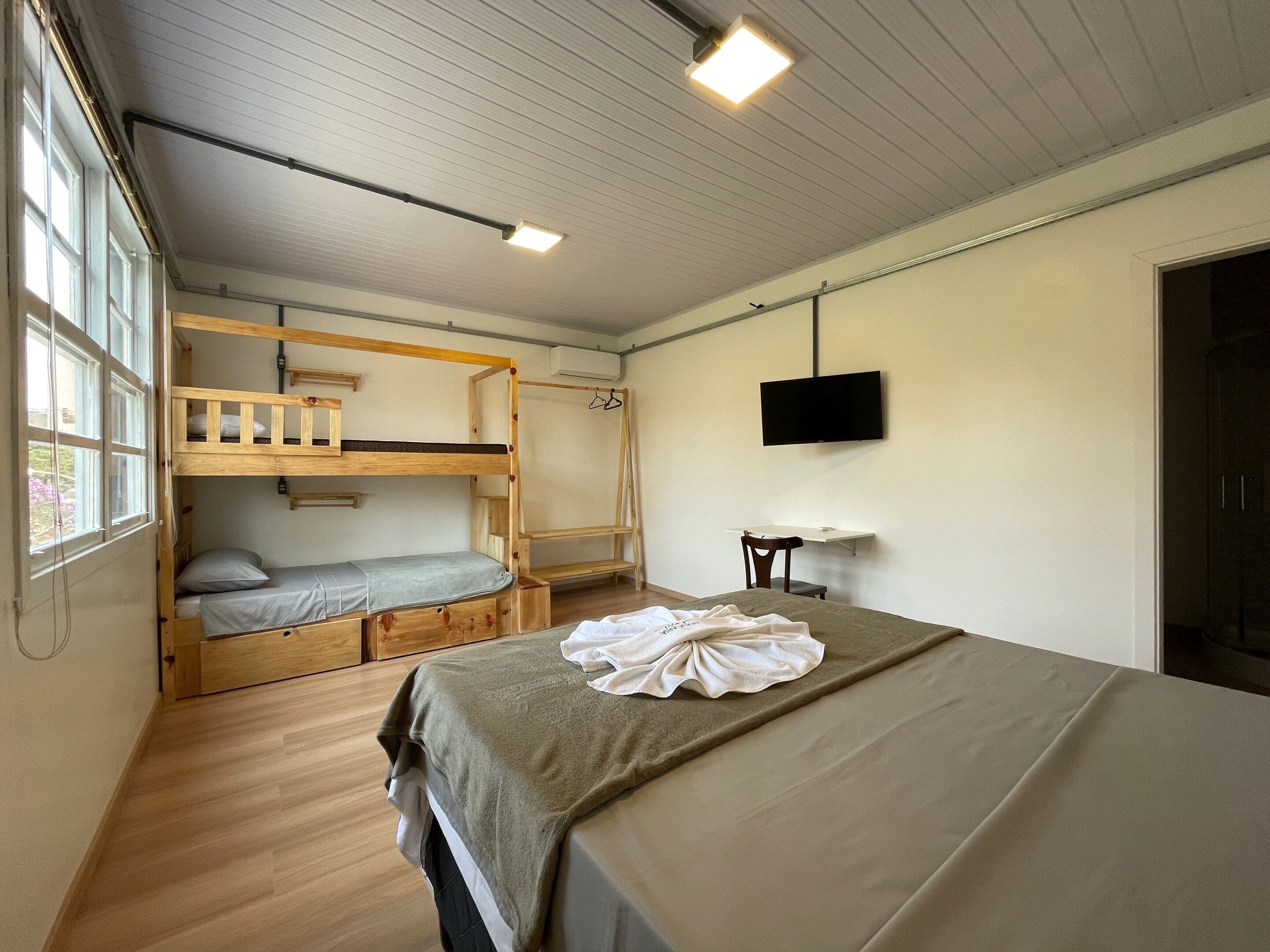 Una camera del dormitorio con letti a castello, una scrivania, una sedia, una TV e una finestra.