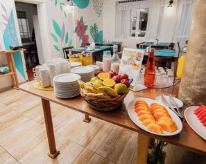 Um buffet de café da manhã com pratos, tigelas e uma cesta de frutas.