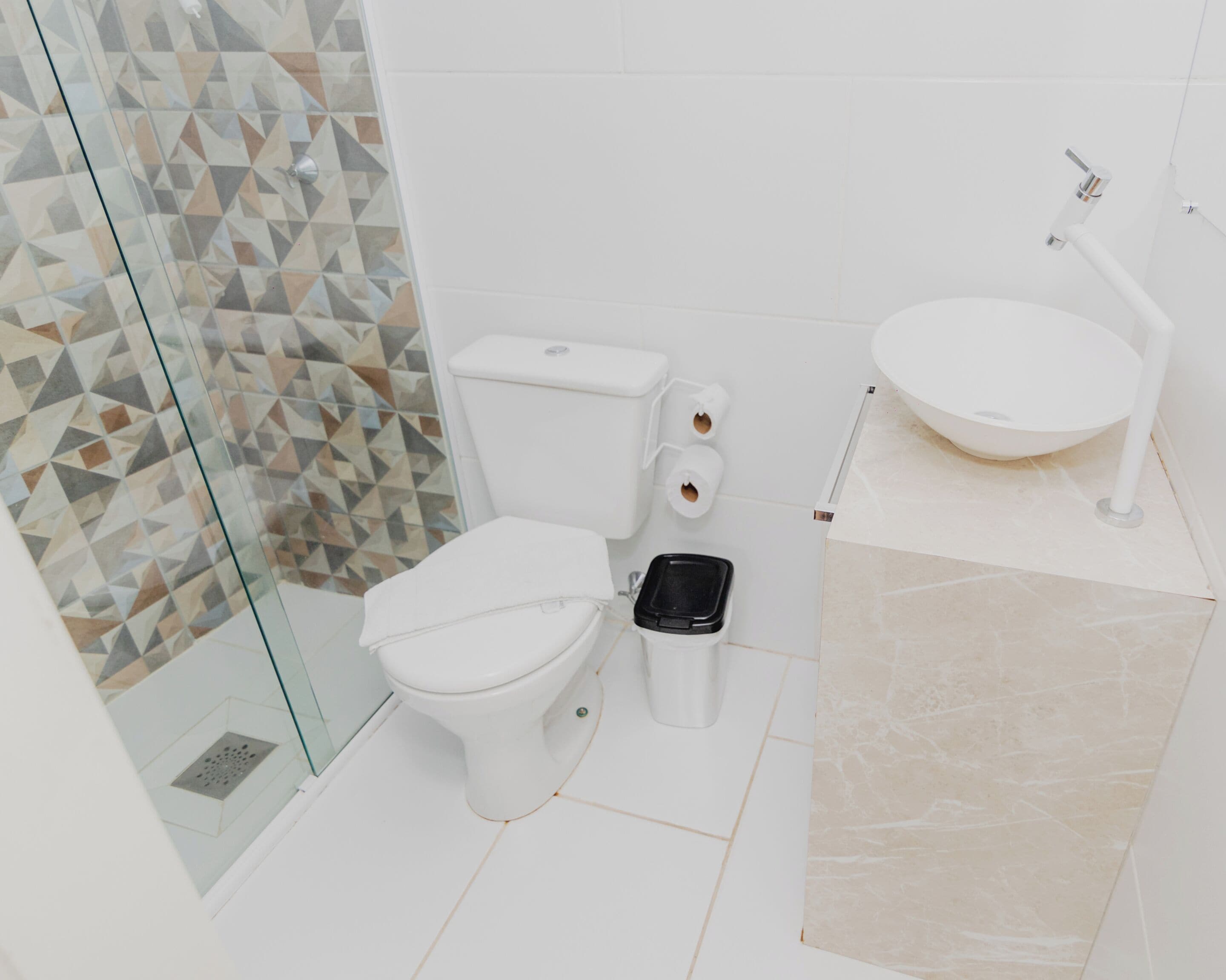 Un baño moderno con cabina de ducha de vidrio, inodoro blanco, bidé y lavamanos con espejo.
