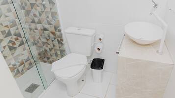Un baño moderno con cabina de ducha de vidrio, inodoro blanco, bidé y lavamanos con espejo.
