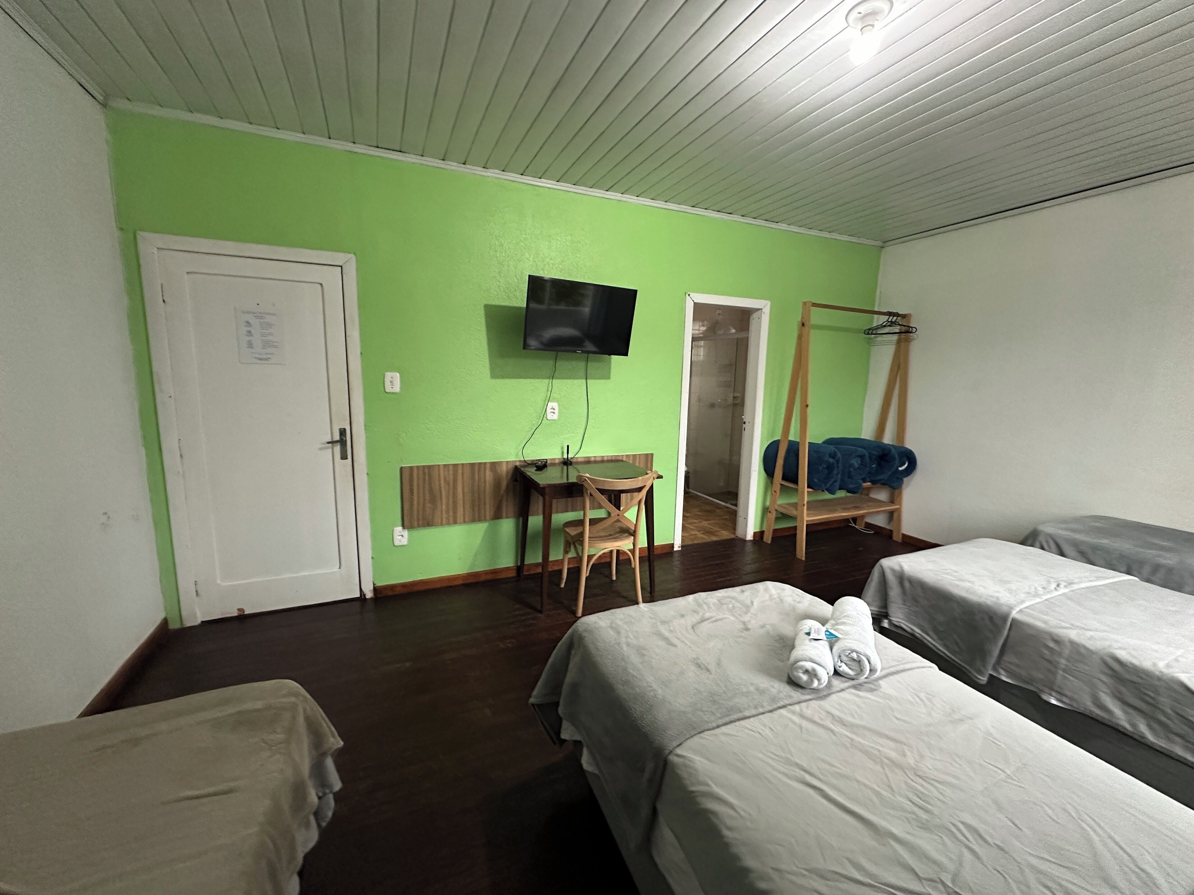 A room with two beds, a desk, a chair, a TV, and a wardrobe.