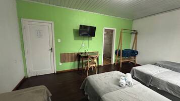 A room with two beds, a desk, a chair, a TV, and a wardrobe.