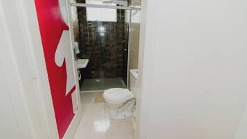 A bathroom with a toilet, a shower, and a sink.