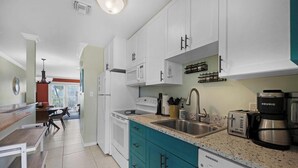 A modern kitchen with white cabinets, a teal countertop, and a built-in dishwasher.