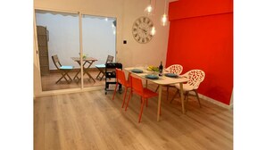Un comedor con una mesa de madera, sillas naranjas, una pared de acento roja y un reloj.