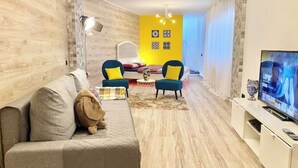 Una sala de estar moderna con un sofá, dos sillones, un televisor y una alfombra estampada.