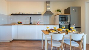 Una cocina moderna con armarios blancos, encimera de madera y un comedor con sillas blancas.