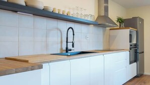 Una cocina moderna con encimera de madera, grifo negro, campana extractora de acero inoxidable y horno integrado.