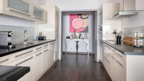 Eine moderne Küche mit weißen Schränken, einer schwarzen Arbeitsplatte und einer Glasrückwand. Ein kleiner Küchenblock mit Spüle und einer Dekoration ist ebenfalls vorhanden.